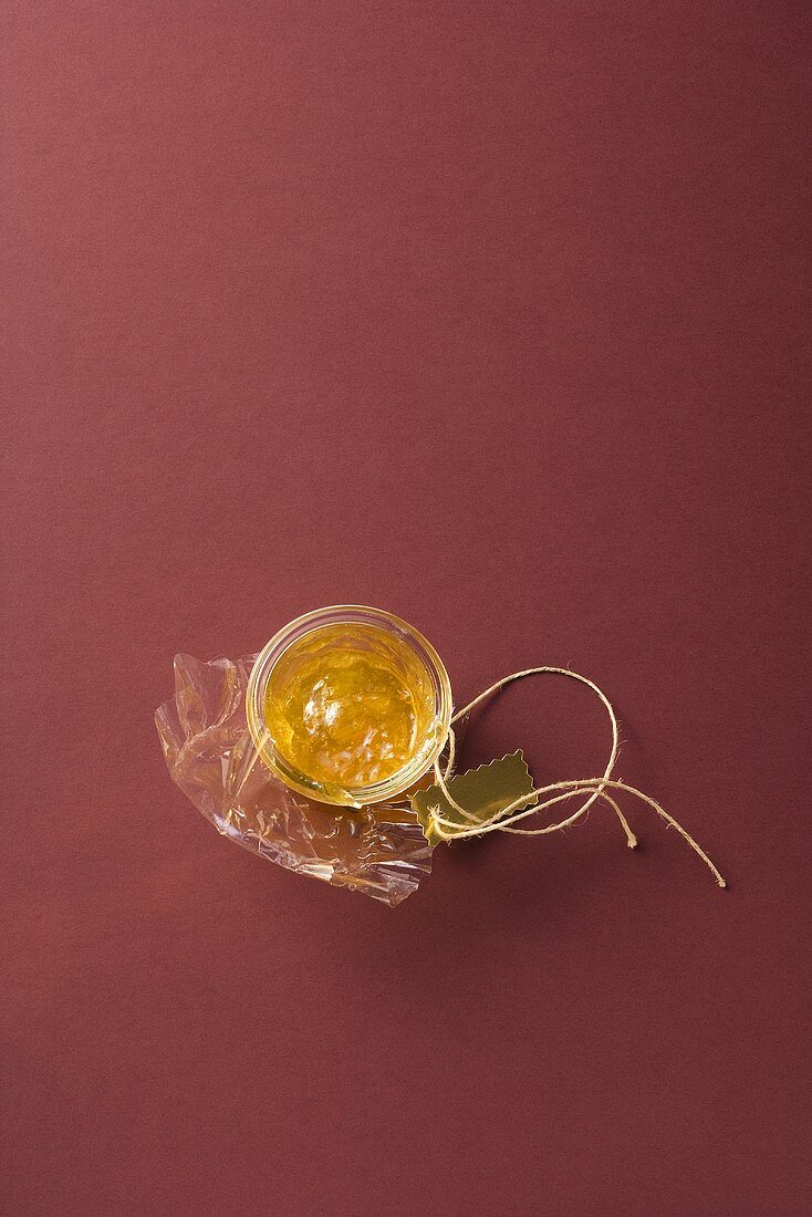 A jar of marmalade with cellophane paper and string
