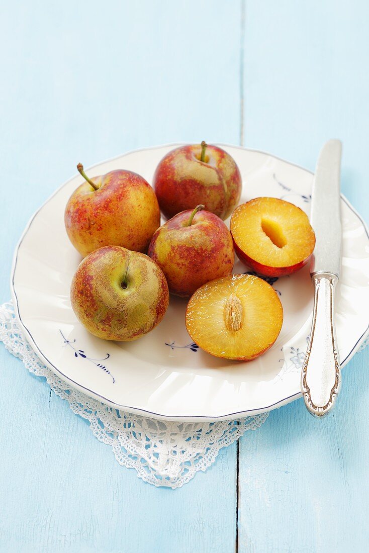 A plate of 'peach' plums (Old English cultivar), whole and halved