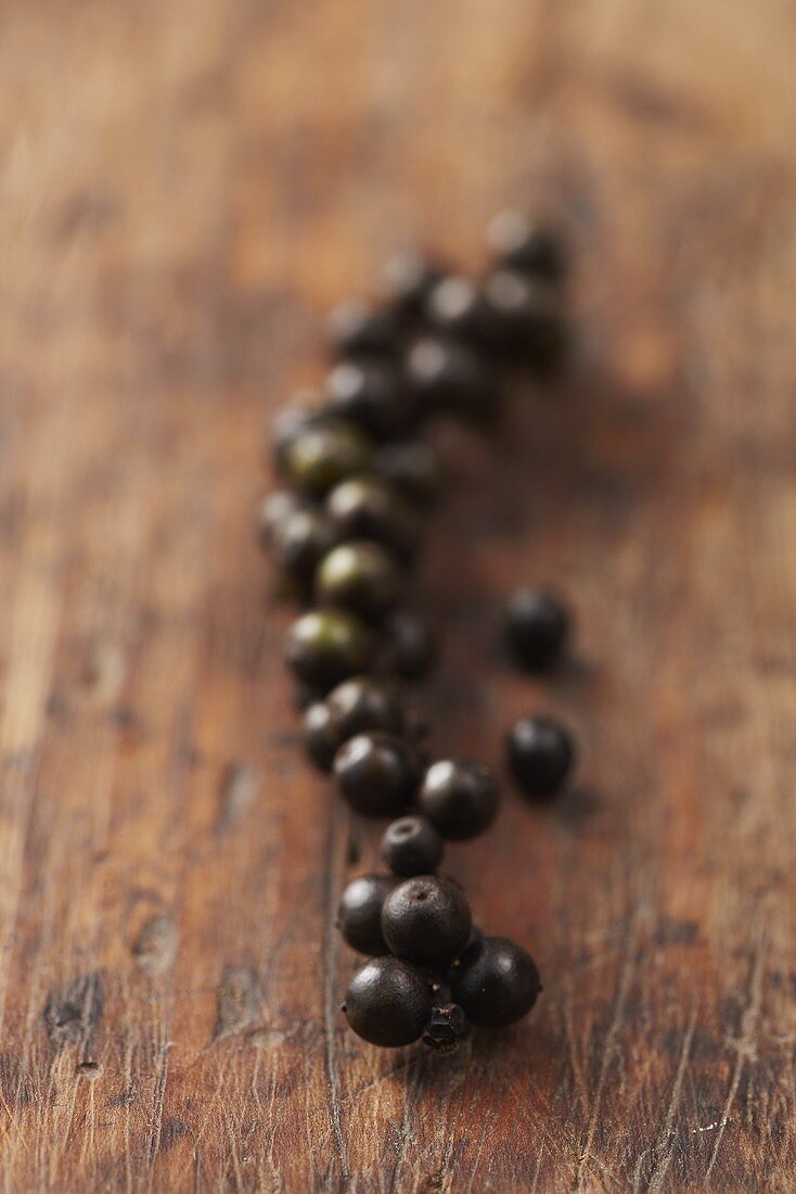 A long row of peppercorns on a wooden surface