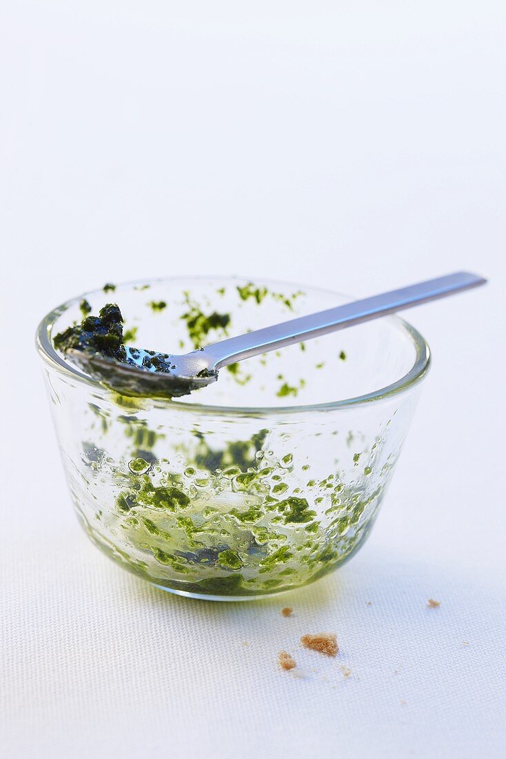 Leftover pesto in a glass bowl with a spoon