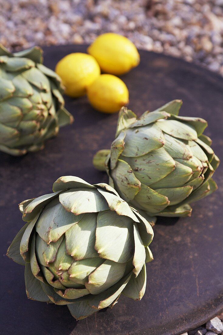 Artichokes and lemons on a black plate