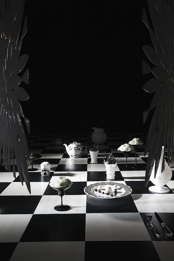 Schwarz-weisser Tisch mit Dessert, Kaffeegeschirr und Blumendeko