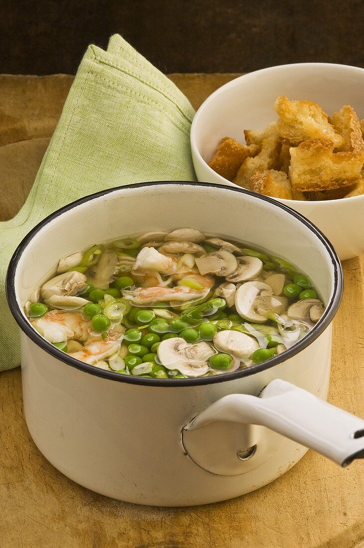 A pot of pea soup with mushrooms and prawns