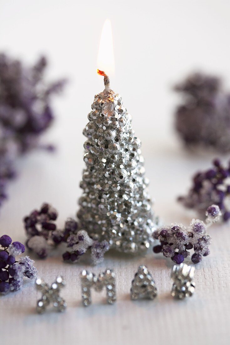 A Christmas candle and writing made of edible pearls with frosted berries