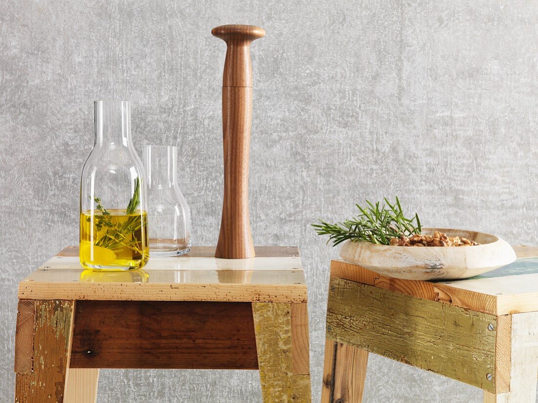 A karaffe of oil and a pepper mill standing on home-made wooden stools
