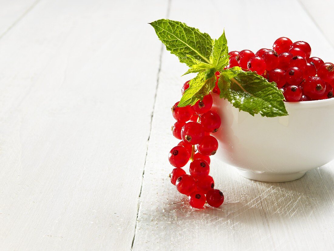 Redcurrants and mint leaves in a bowl