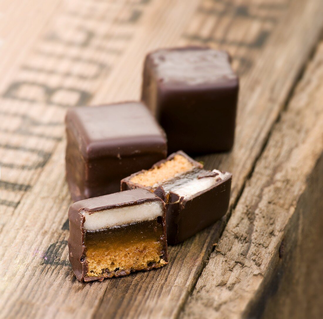 Dominosteine (chocolate covered sweets with marzipan and gingerbread) whole and halved on a wooden crate