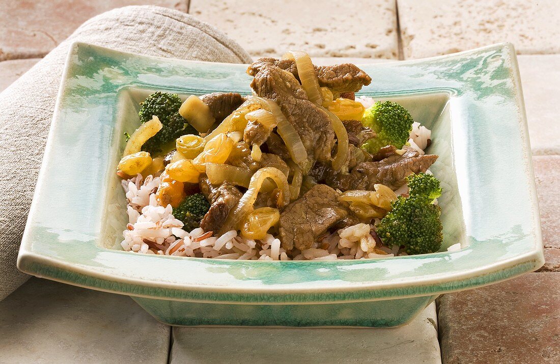 Schweineragout mit Zwiebeln, Rosinen und Brokkoli auf Reis
