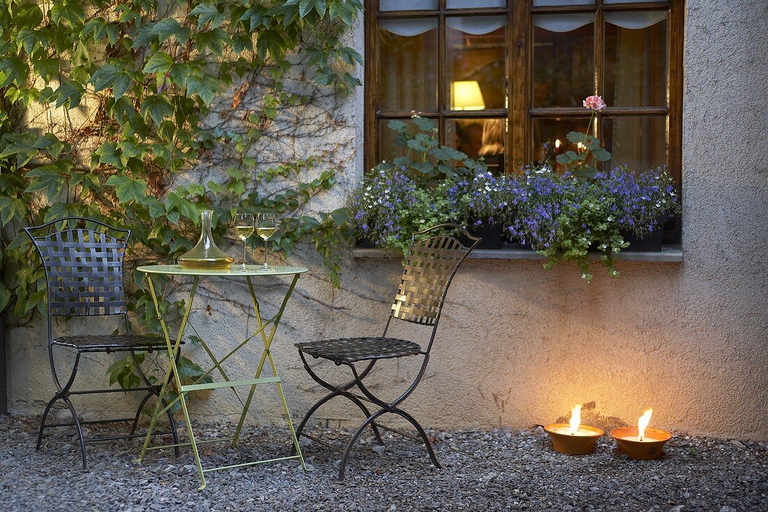 A table laid with wine and tea lights in front of a rustic restaurant