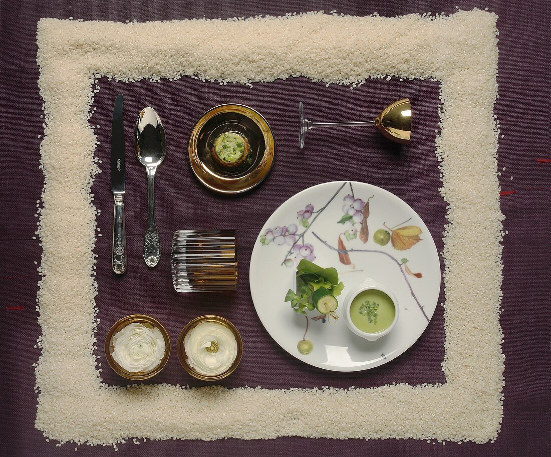 A festive place setting with pea soup and rice pudding framed by grains of rice