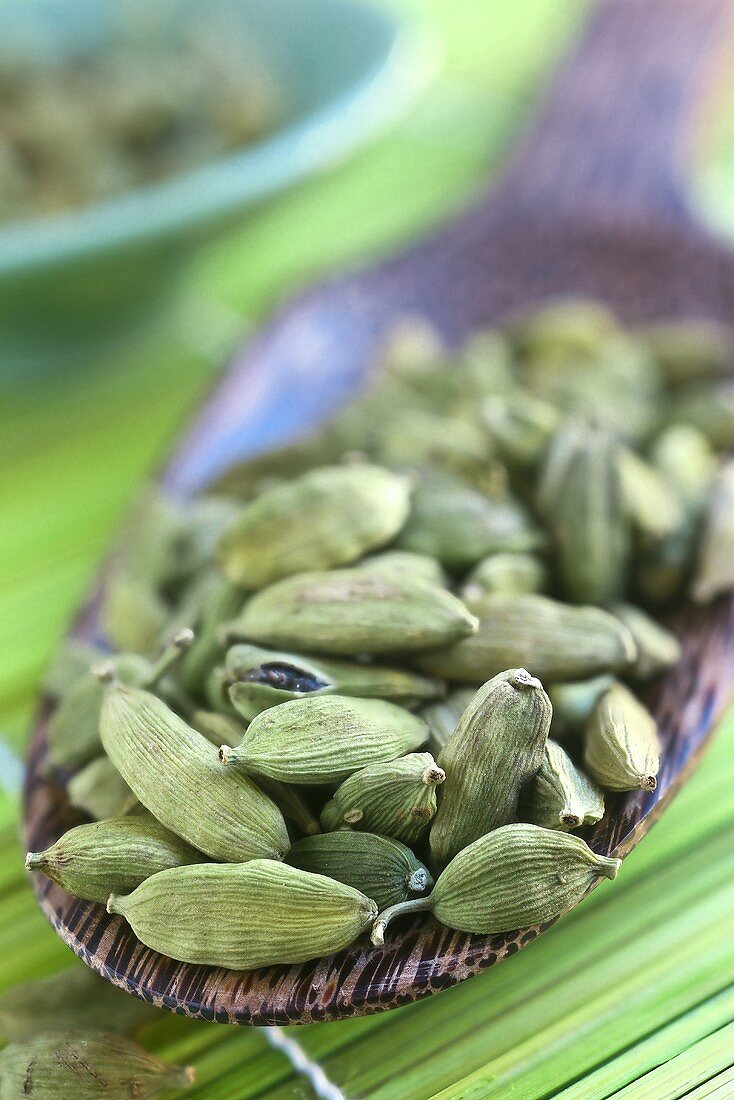 Cardamom pods on a wooden scoop