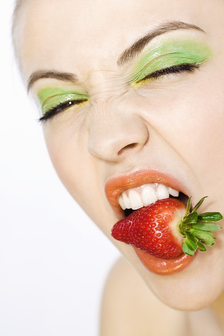 Junge Frau mit einer Erdbeere im Mund