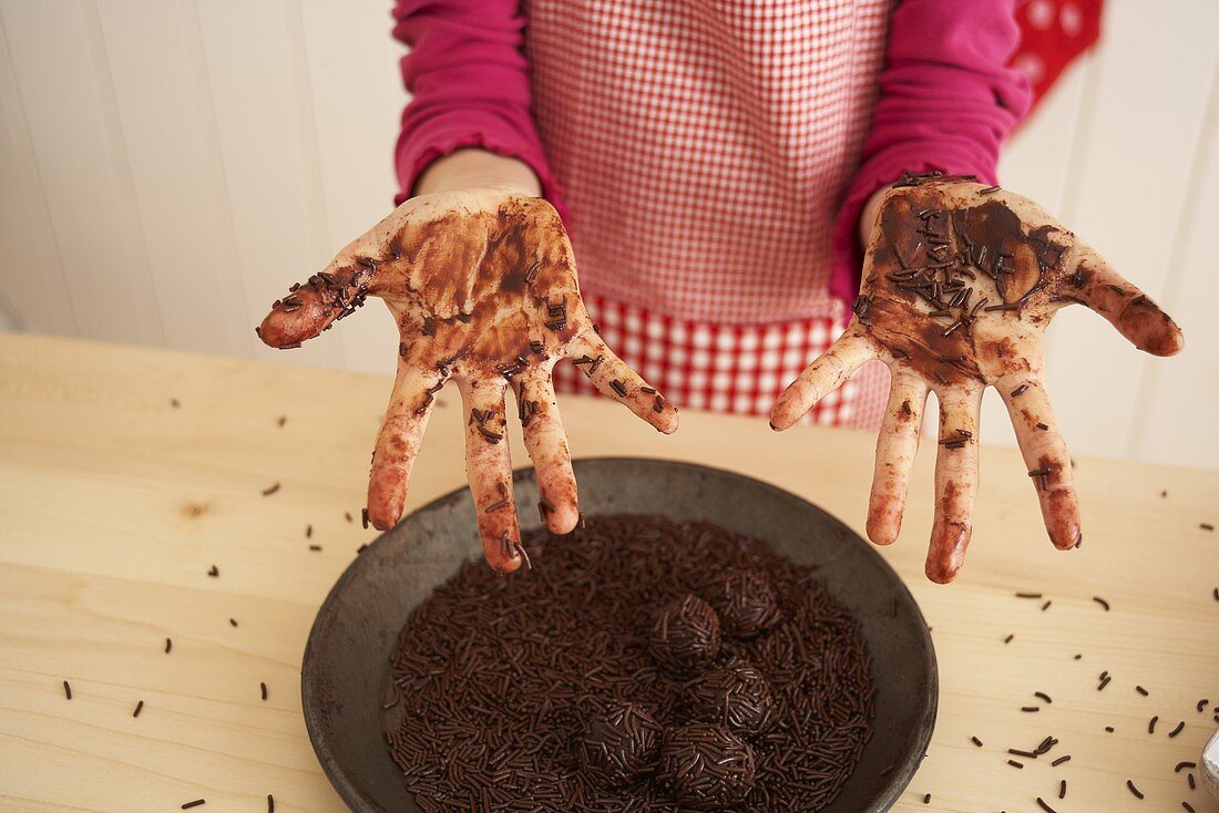 Kind zeigt mit Schokolade verschmierte Hände