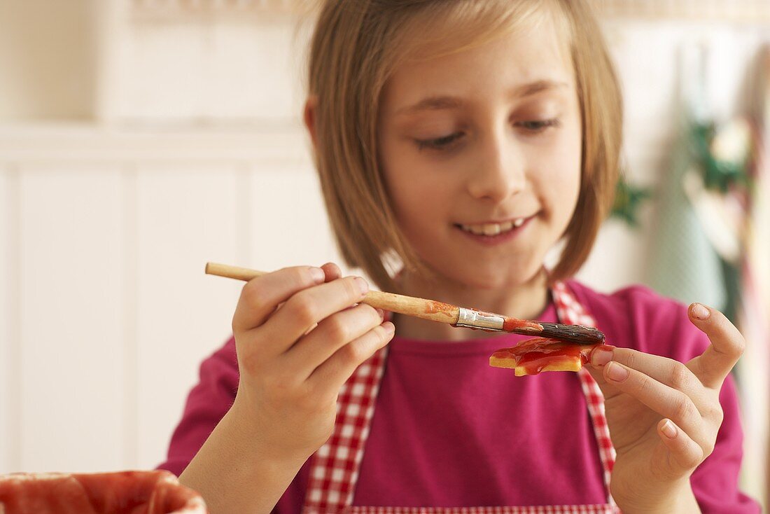 A girl brushing shortbread biscuits with jam