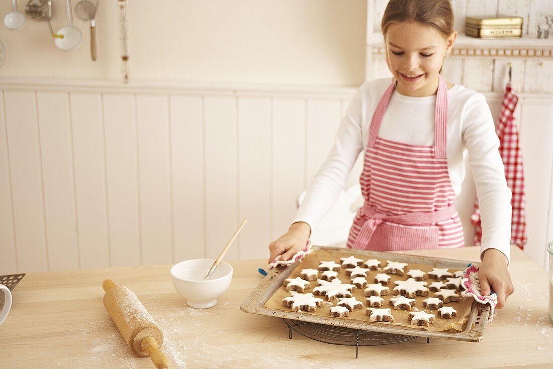 A girl holding a baking tray of cinnamon stars