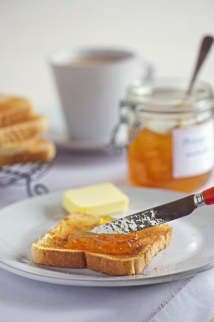 Orangenmarmelade auf Toast schmieren
