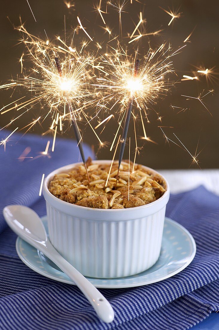 An apple crumble with two sparklers