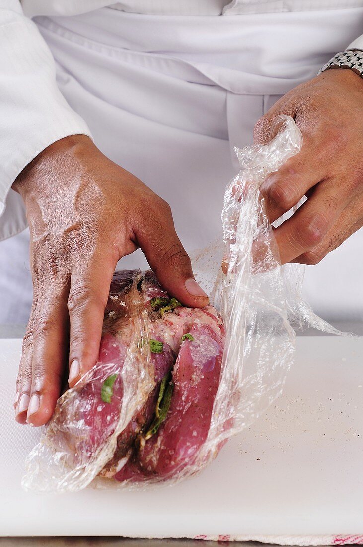 Clingfilm being removed from a pork shoulder joint