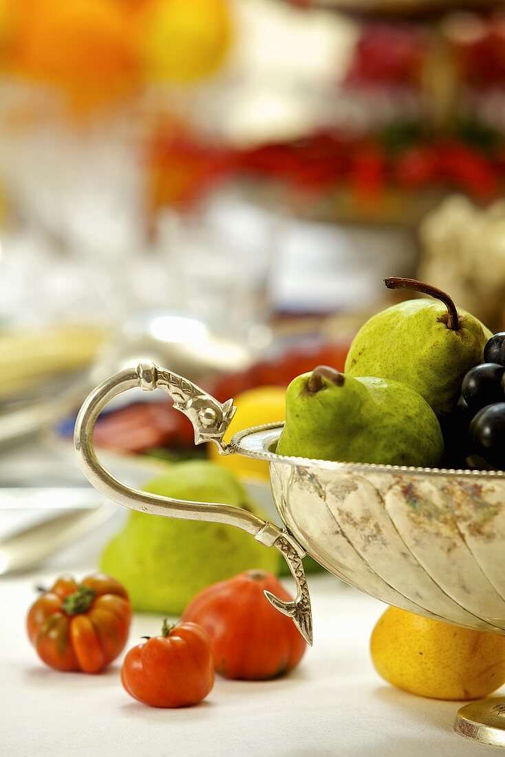 Silberne Obstschale und Tomaten auf Tisch