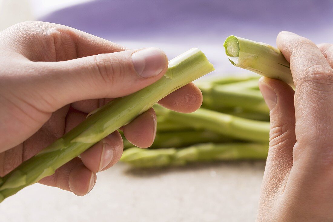 Das holzige Ende vom grünen Spargel abbrechen