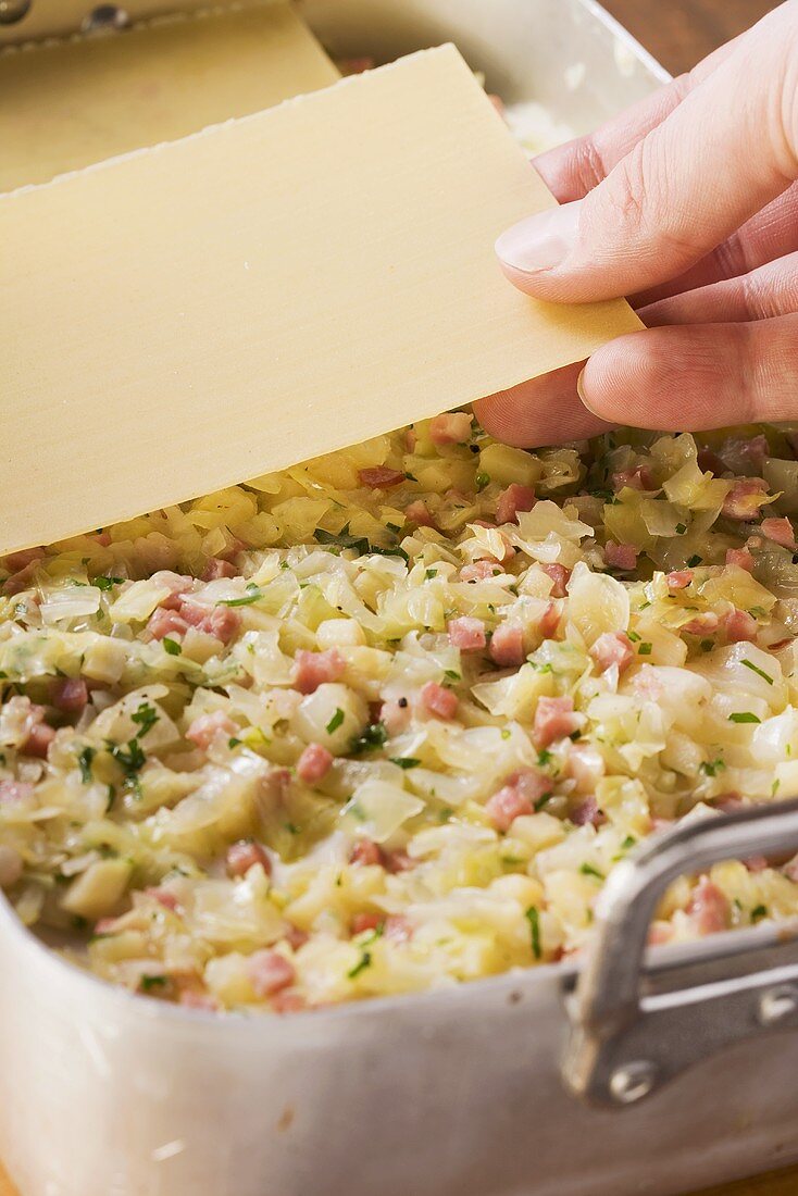 Vegetable lasagne being layered in a baking dish