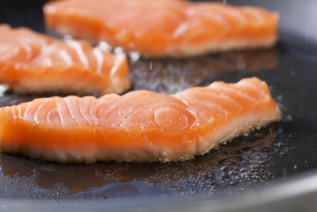 Salmon slices being fried