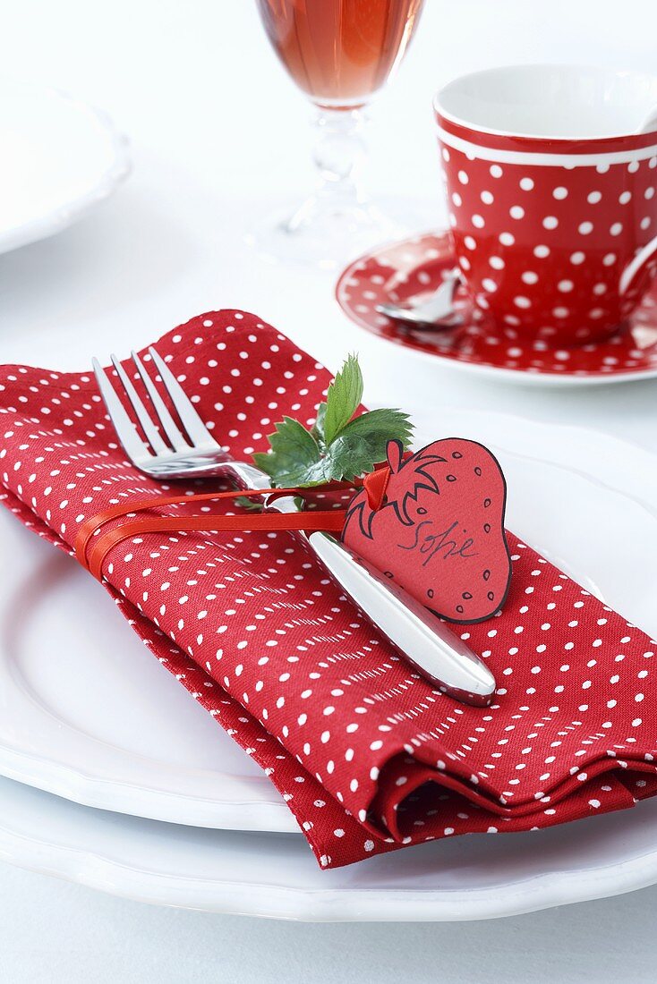 A place setting with a polka dot napkin and a strawberry-shaped label