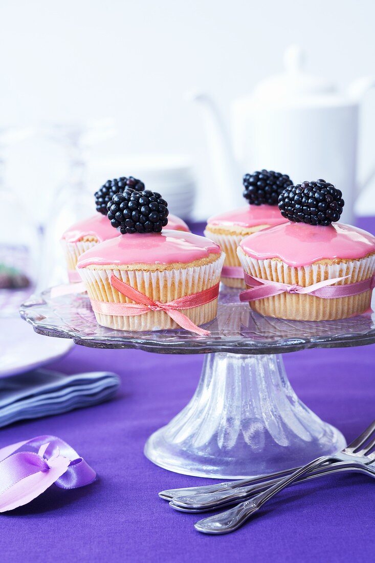 Muffins mit rosa Zuckerguss und Brombeeren