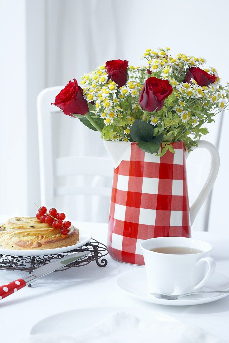 A jug being used as a vase with tea and cake with redcurrants