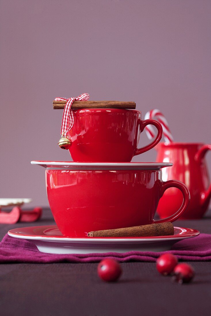 A red espresso cup and a coffee cup with cinnamon sticks
