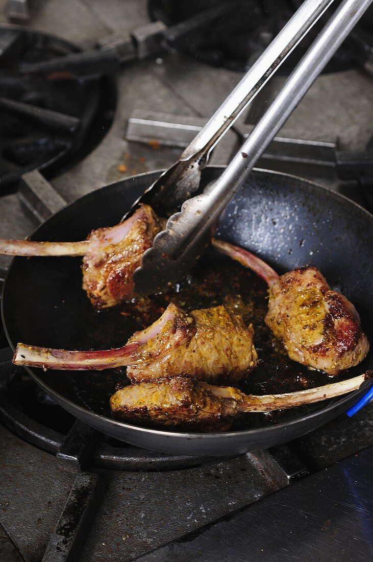 Lamb chops being fried in a pan