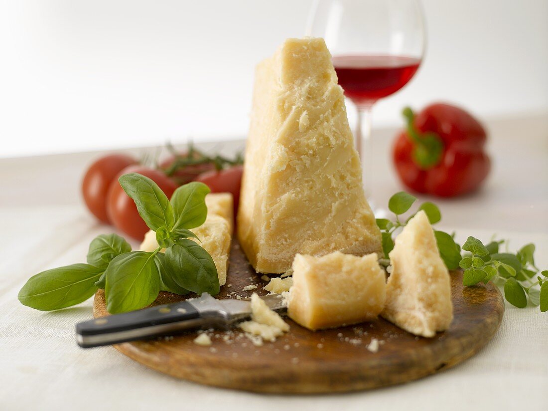 A piece of Parmesan with knife and basil