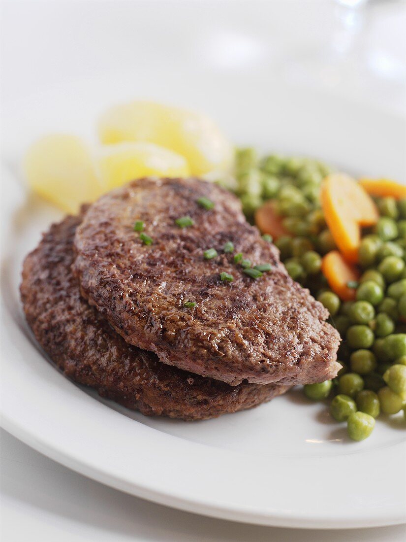 Hamburger steaks with peas and carrots