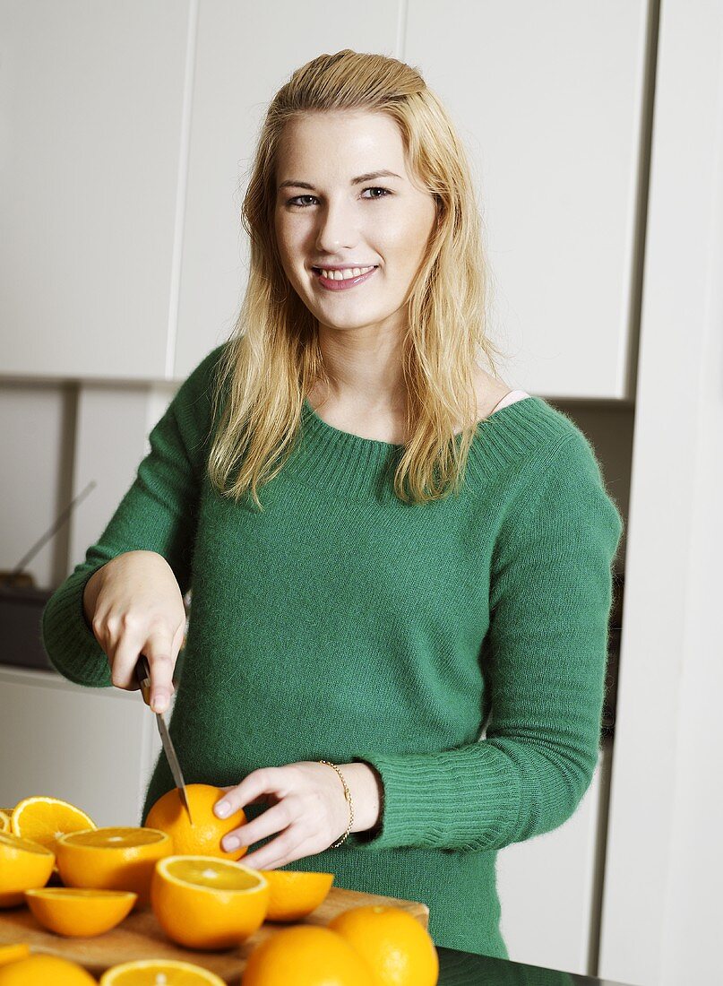 Woman halving fresh oranges