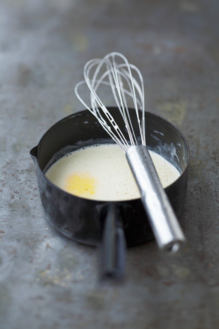 Weißwein-Sahnesauce in einer Stielcasserole mit Schneebesen