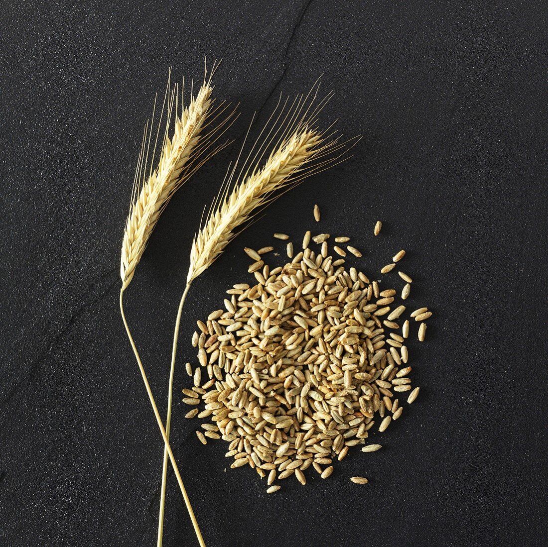 Ears and grains of rye on stone background