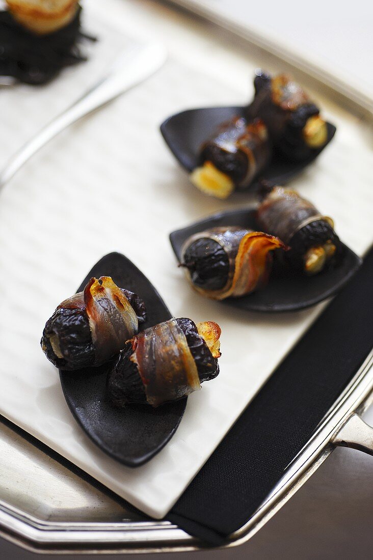 Bacon-wrapped prunes stuffed with goat's cheese on tray