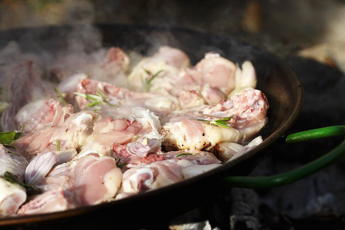 Chicken pieces in smoking frying pan
