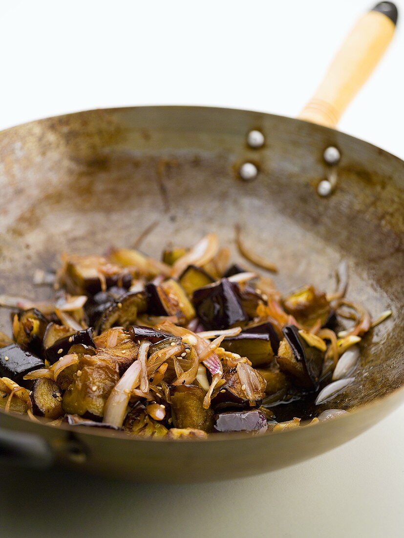 Fried aubergines with onions and sesame seeds in wok