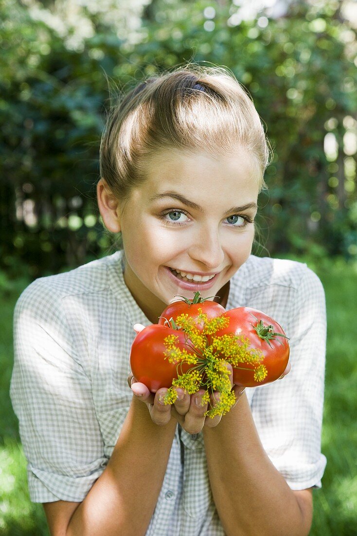 Frau hält Tomaten und Dill im Garten