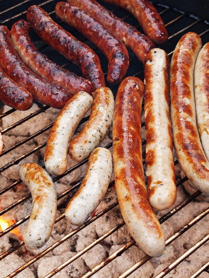Various types of sausages on a charcoal barbecue