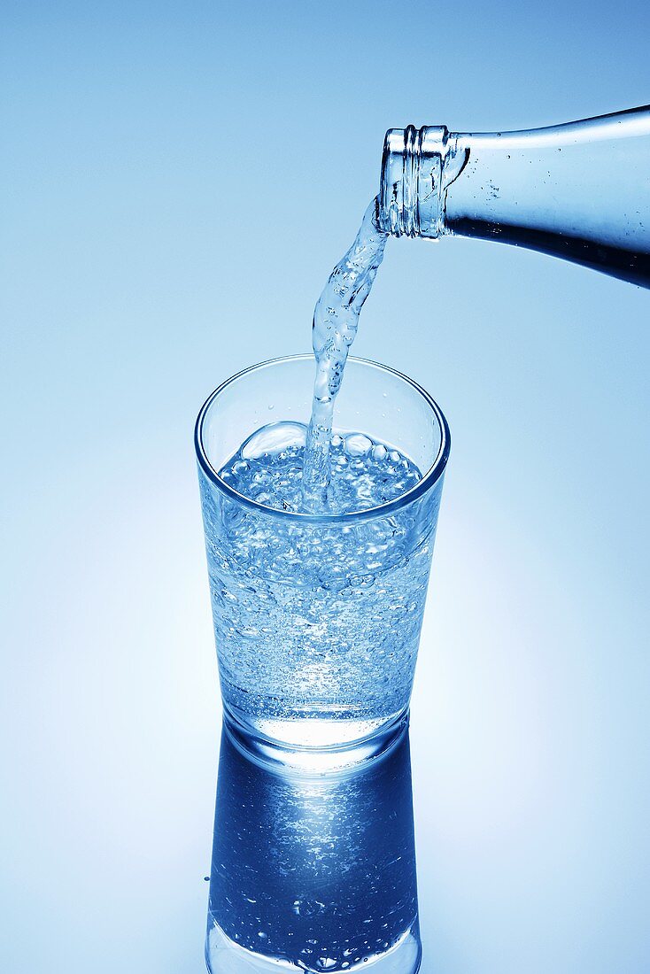 Mineralwasser in Glas einschenken