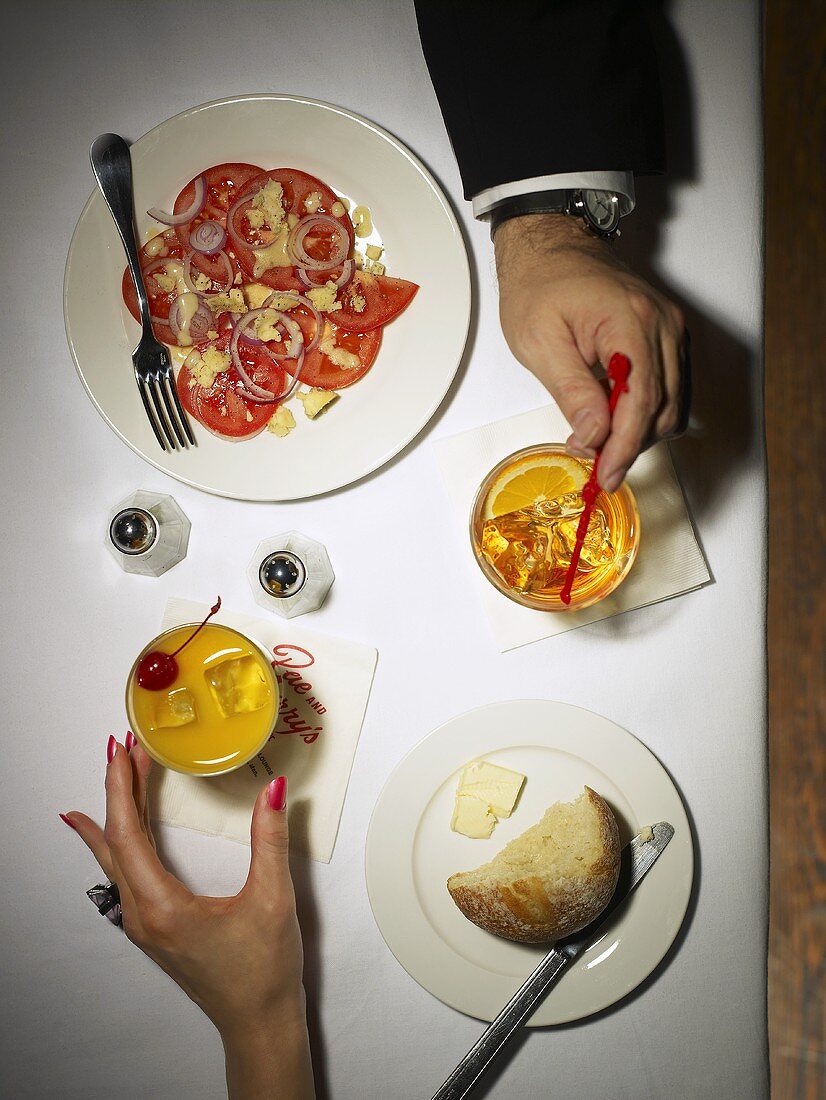 Männer- und Frauenhand am Tisch mit Drinks und Vorspeise