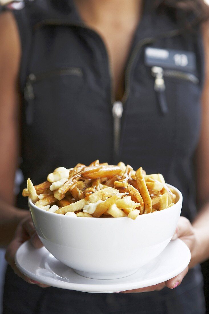 Woman holding poutine (Chips with cheese curds & gravy, Canada)