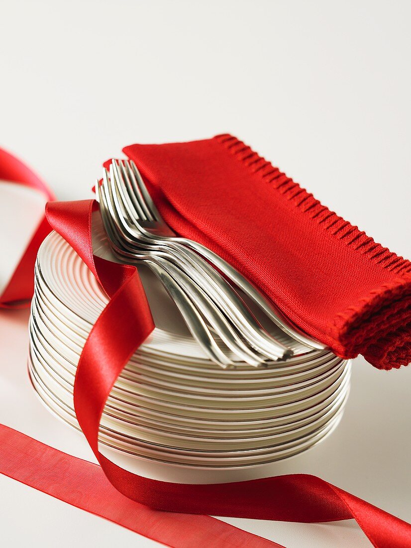 Stack of plates, forks, red napkins and ribbon