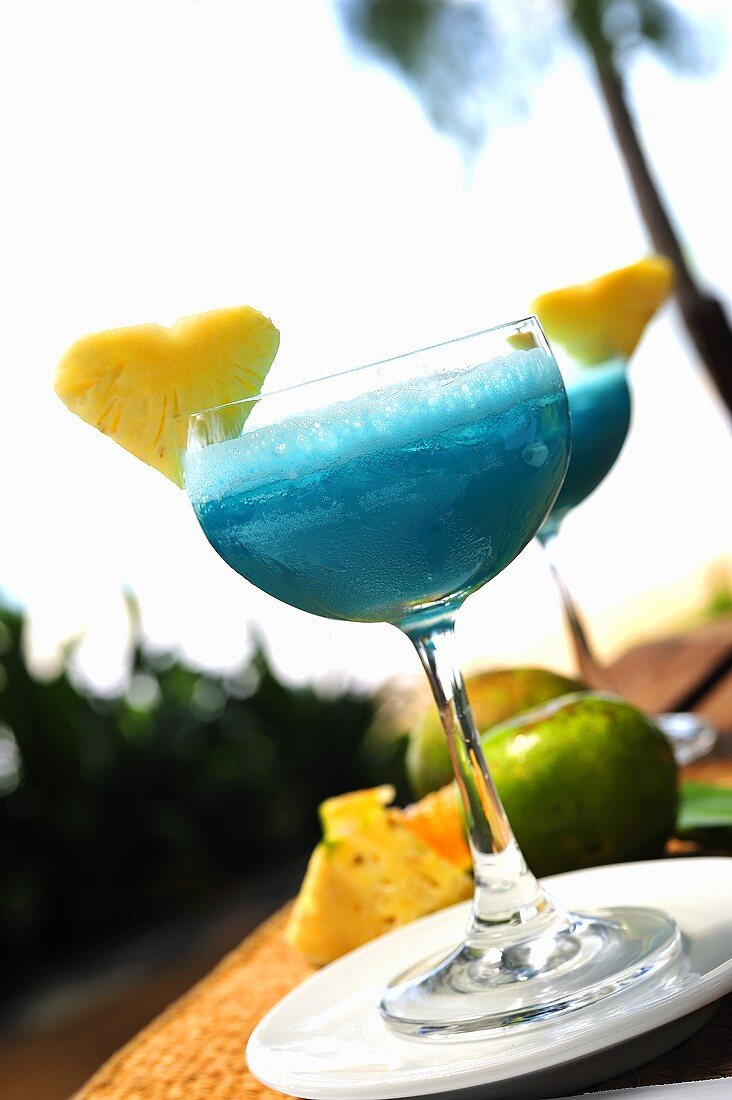 Blue Curacao Drink mit Ananasherz auf Tisch im Freien