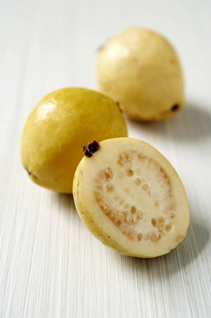 Two whole yellow guavas and half a guava