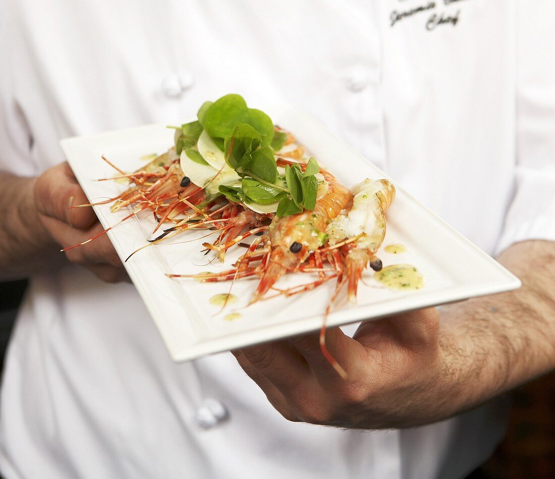 Chef holding prawns with cress salad