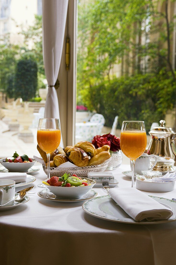 Fruit salad, multivitamin juice & pastries on breakfast table