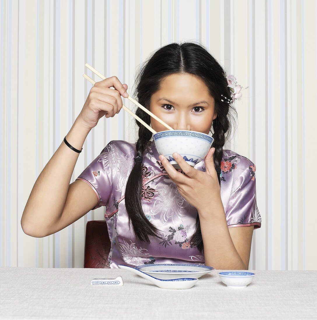 Asian woman eating with chopsticks